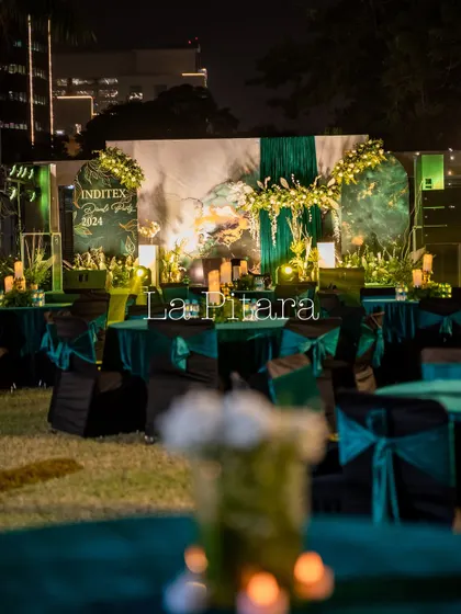 Another perspective of the outdoor lawn setup, showing the arrangement of tables and the beautifully lit stage in the background, ready for an evening of celebration.