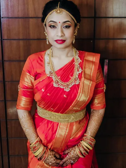 A beautiful portrait showcasing the complete muhurtham look. The makeup is balanced, with defined eyes and a bright lip color that enhances her features.