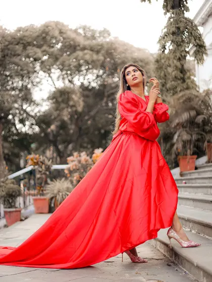 An elegant outdoor portrait that has a studio feel, featuring a model in a flowing red gown.