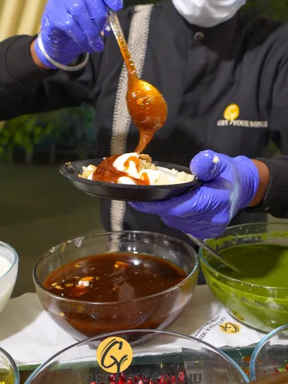Our chefs take great care in preparing each plate of chaat. Here, a chef is adding the final touch of sweet tamarind chutney to a dish of Dahi Bhalla.