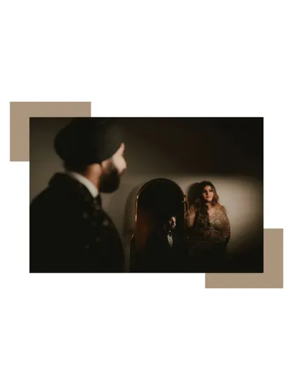 An artistic shot using a mirror to create a sense of depth and reflection. The groom looks at his bride's reflection, adding a layer of creative storytelling.