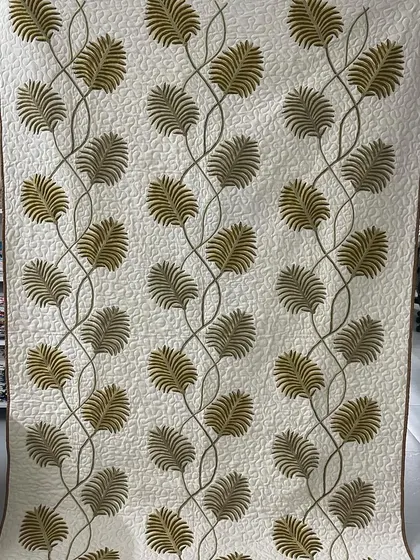An elegant wall hanging featuring appliqué vines with delicate leaves, quilted to create a sense of dimension.