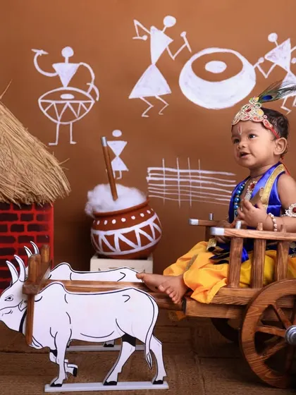 Looking up with wonder, this little Krishna is perfectly posed in our detailed village scene setup, complete with a hut, cow, and traditional art.