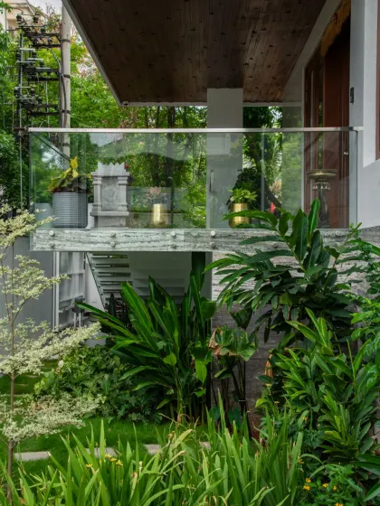 This design showcases a perfect blend of architecture and landscape. A glass-railed balcony overlooks a densely planted garden, creating a harmony between the clean lines of the home and the organic forms of nature.