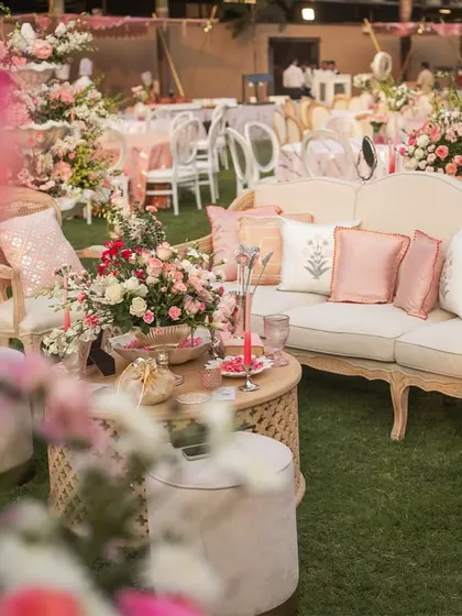 A comfortable lounge area at the 'Gulab Bagh' wedding, with custom-printed cushions and beautiful floral arrangements.