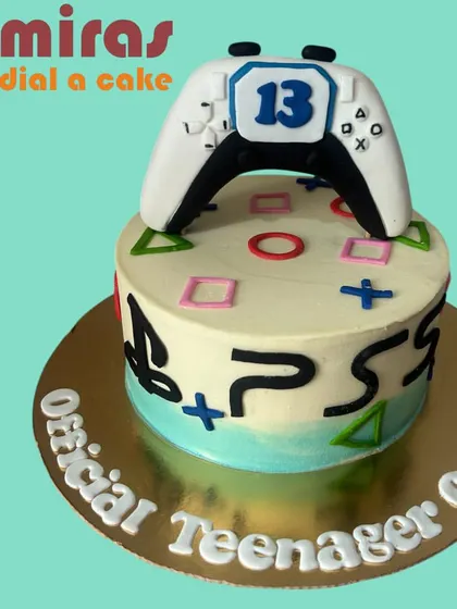 Game on! This PlayStation-themed cake is perfect for an official teenager's birthday. It features a sculpted controller on top and the iconic button symbols around the sides, celebrating a passion for gaming.