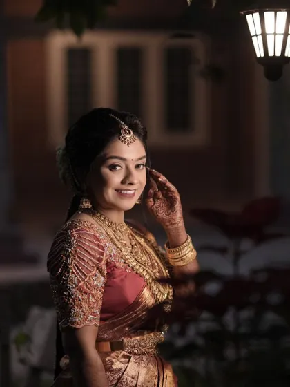 A beautiful outdoor shot of the bride on her Muhuratam day. The classic red saree and red lip are timeless choices, creating a look that is both traditional and stunning.
