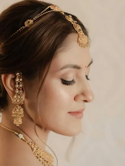 A close-up on the soft, glowing makeup and the delicate details of the hairstyle. This look is all about enhancing natural beauty with a touch of glam.