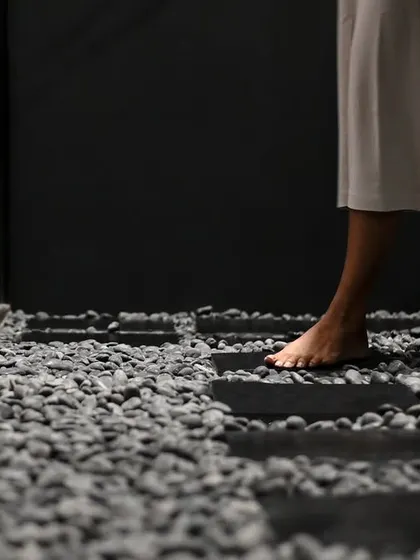 We believe the customer's journey is a tactile one. The use of rough pebble stone flooring is a deliberate choice to slow the visitor's pace, encouraging a mindful, deliberate traversal of the space and a heightened awareness of the physical environment.