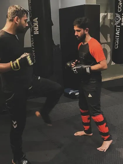 An instructor holds pads for a student, guiding him through a kicking combination. This is a fundamental part of our training, building power, accuracy, and muscle memory.