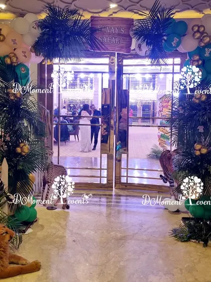 A sophisticated jungle-themed entrance featuring lush palm trees, animal props, and a wooden "Safari" sign, creating an elegant adventure vibe.