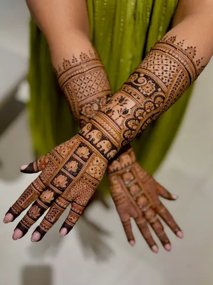 A crossed-hands pose of the lotus and elephant block-patterned mehendi.
