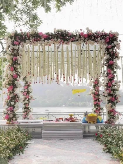 A clean and elegant mandap design with a floral arch and hanging tuberose strings, perfect for a serene daytime ceremony.