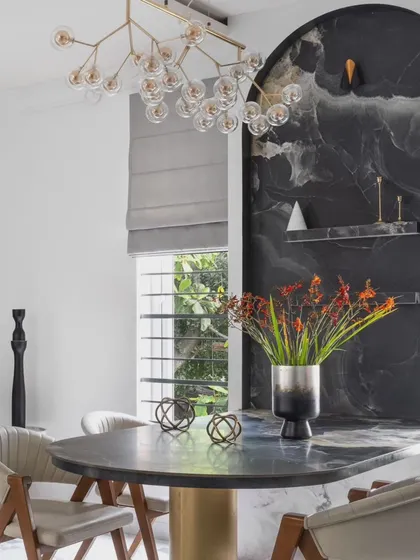 For Dr. Harsha's home, we created a dramatic dining nook with a custom-built table integrated into a monolithic dark tile wall. This space-saving solution becomes a bold statement piece, contrasting beautifully with the home's otherwise light and airy feel.