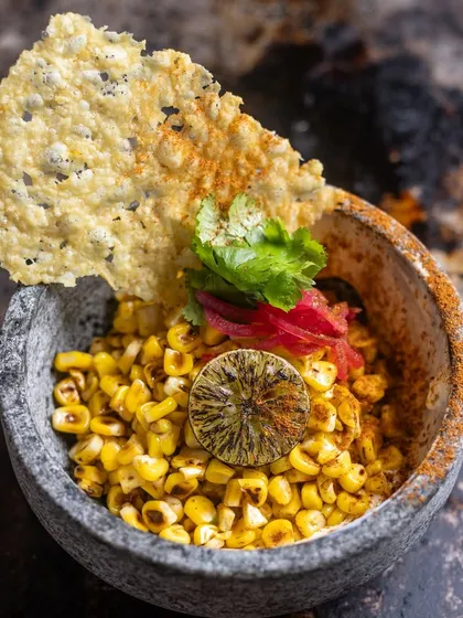My take on Esquite. I char fresh corn kernels and toss them with aioli, cilantro, and confit garlic, served with a parmesan crisp. It's a smoky, creamy, and tangy appetizer inspired by Mexican street food.
