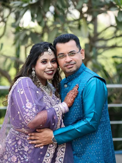 A classic portrait of an engaged couple, smiling warmly for the camera in their traditional attire.