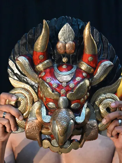A stunning Nepali mask with brass and copper metalwork. This unique piece combines wood carving with metal detailing, reflecting a high level of artistry and cultural significance.
