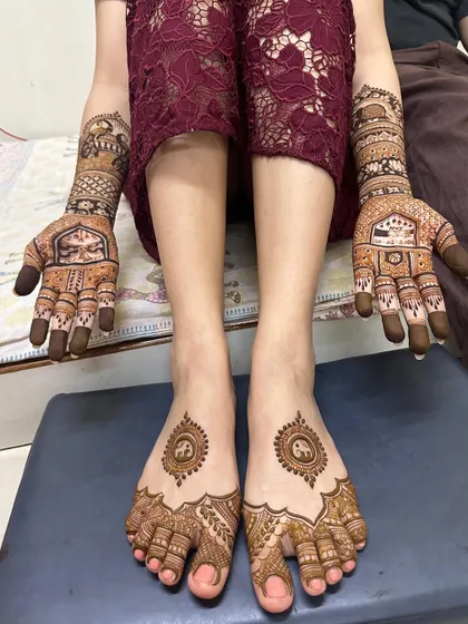 The full view of Yesha's bridal mehendi, showing the beautiful figures on her palms and the coordinated design on her feet.