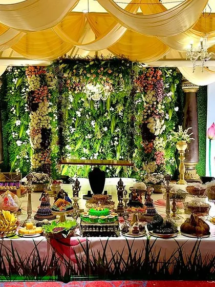 The full display of traditional offerings at a half-saree ceremony, set against our vibrant, custom-designed backdrop featuring a green wall and Pichwai-style art.