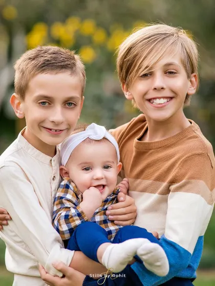 The three siblings together! The two older brothers proudly hold their baby sister, creating a portrait that is overflowing with love and family connection.