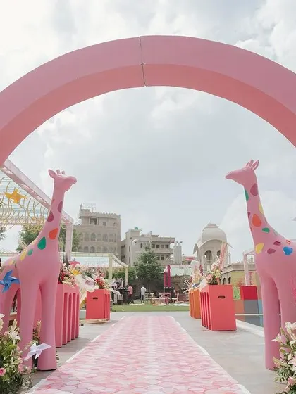 The grand entrance to the carnival Mehendi, marked by a large pink arch and flanked by two playful giraffe statues, setting a fun and festive tone.