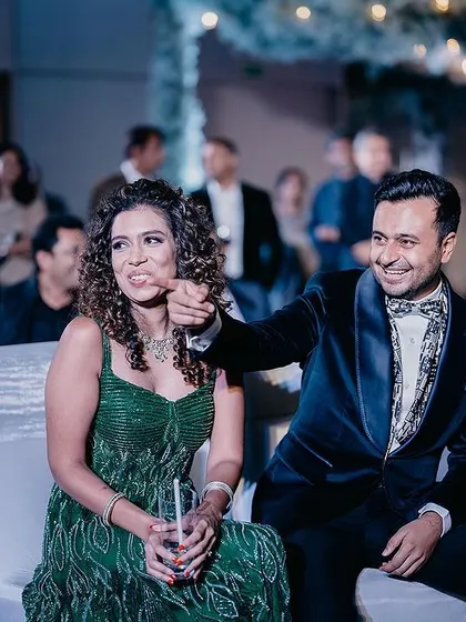 A couple enjoys a lighthearted moment during their reception, surrounded by friends and family.
