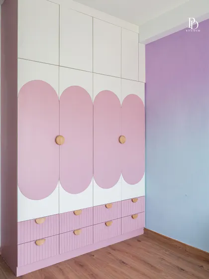 For this child's room, we designed a playful wardrobe with pink scalloped panels and simple wooden knobs. The design is whimsical yet functional, with ample drawer storage below for toys and clothes.