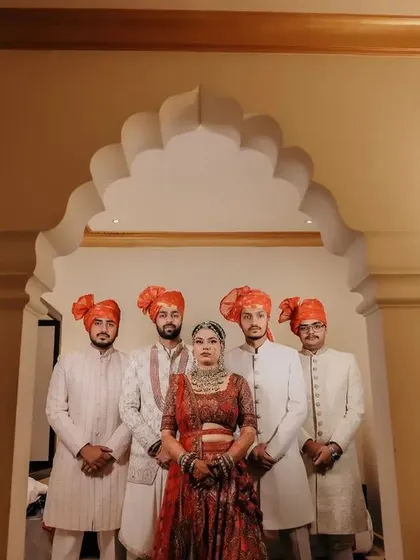The bride posing with the groomsmen, all in coordinated traditional attire.