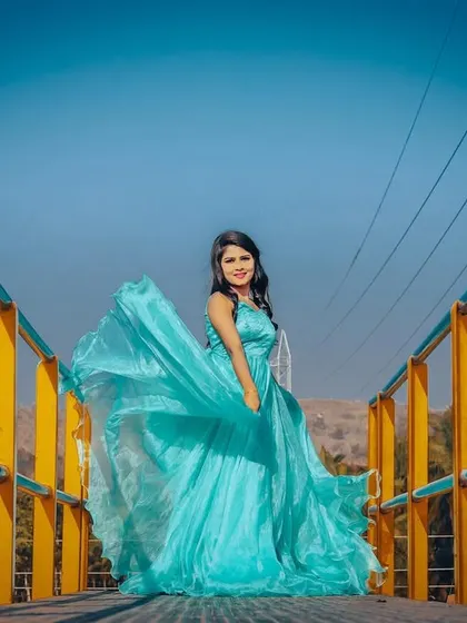 The full glory of the light blue gown is visible in this shot on a bridge, with the wind catching the layers of fabric.