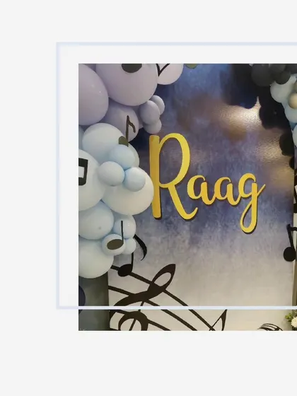 A close-up of the custom 'Raag' name sign against the blue watercolor-effect backdrop.