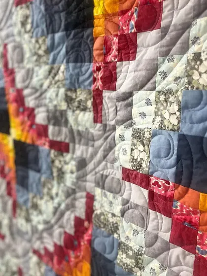 A close-up of a fiery geometric quilt, showing the swirling quilting pattern.