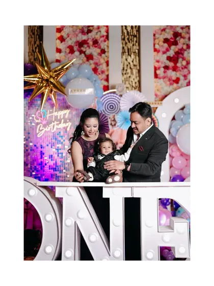 The birthday boy with his parents at his beautifully decorated party. The "ONE" marquee lights add a special touch to this family portrait.
