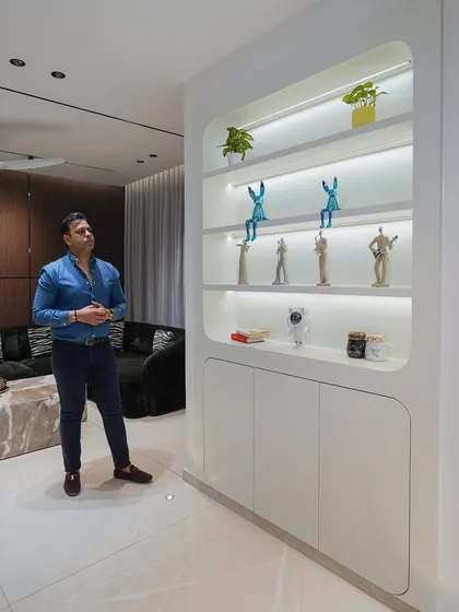 Here I am in a completed living room, showcasing the custom-designed display unit. The rounded corners and internal lighting create a soft, modern showcase for decor items.