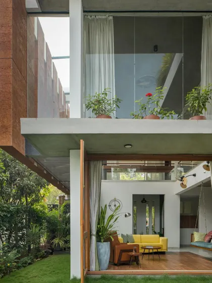 Another angle showing the cantilevered upper floor, which provides shade for the ground floor patio. The use of laterite stone adds a warm, earthy texture to the facade.