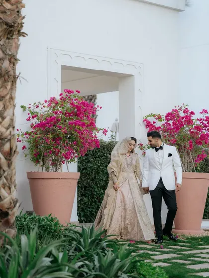 A romantic walking shot of the couple, hand in hand, past vibrant bougainvillea flowers.