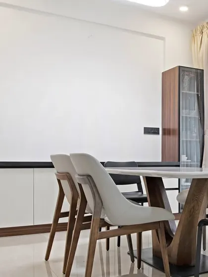 This dining space is designed for easy conversations and everyday comfort. The mix of light and dark tones, a clean-lined crockery unit, and soft natural light make it both stylish and functional.