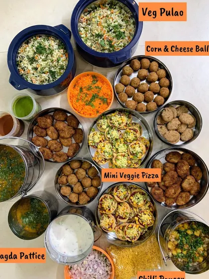 A festive spread for a Raksha Bandhan celebration. The menu included Veg Pulao, Corn & Cheese Balls, Mini Veggie Pizza, and Ragda Pattice.