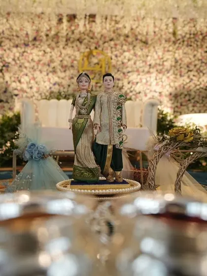 A creative shot focusing on the engagement rings, with the decorated stage and couple dolls visible in the background.