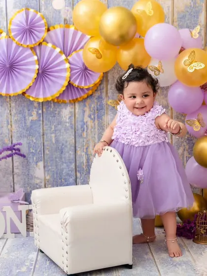 Celebrating one year with a lovely lavender and gold theme. This little girl stands proudly by her chair, ready for her party.