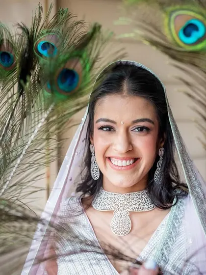 A joyful portrait of the bride, framed by peacock feathers. This creative choice is another nod to her love for Krishna, making the photo deeply personal.