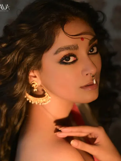 A striking close-up portrait for a 'Shubho Noboborsho' campaign. The model's intense gaze, bold kohl-rimmed eyes, and traditional nose ring create a powerful and dramatic look.