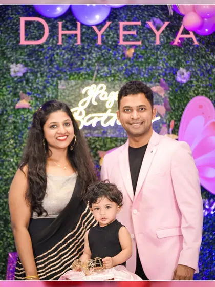 A classic family portrait taken at a first birthday party. The beautiful butterfly-themed backdrop and neon sign add a modern and personalized touch to the event decor.