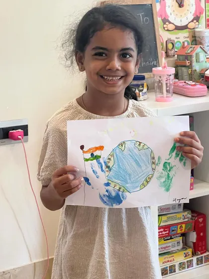 This smiling artist is proud of her Earth Day creation, complete with handprints and the Indian flag.