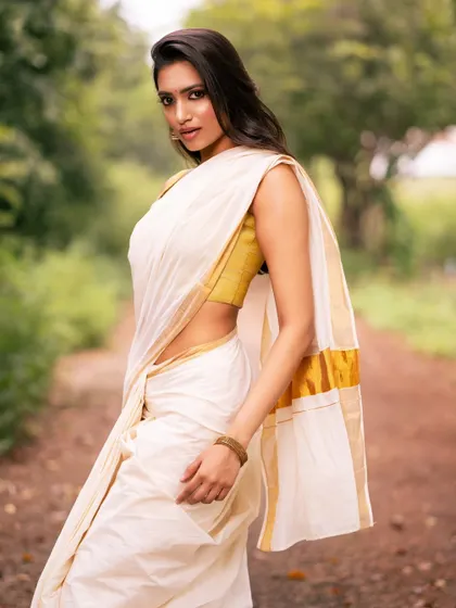 A profile shot of a model in a white and gold saree, capturing a moment of quiet elegance.