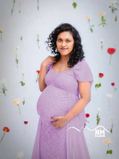 Another beautiful portrait from our 'life-in-bloom' setup. The simple, clean background with floating flowers puts all the focus on the expecting mother and her radiant smile. This purple lace gown is a client favorite for its elegance.
