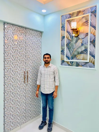 Here I am standing next to the geometric patterned wardrobe in the blue bedroom. The design is modern and eye-catching.