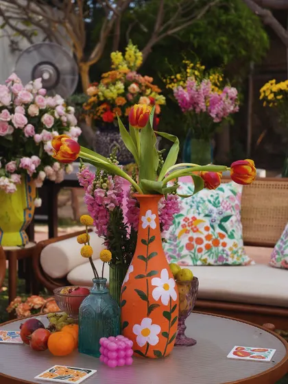 A detail shot of a hand-painted vase with a daisy motif, filled with tulips, adding to the artistic and whimsical feel of the decor.