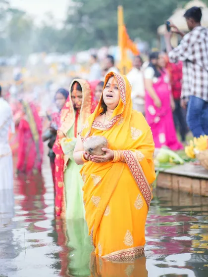 A woman sings devotional songs while standing in the water during Chhath Puja. Music and chanting are an important part of expressing devotion.