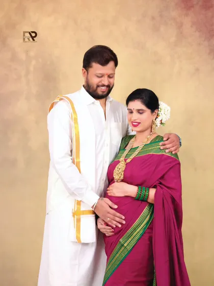 A classic portrait of the couple in traditional attire. The warm, neutral backdrop ensures that the focus remains on their happy expressions and beautiful outfits.