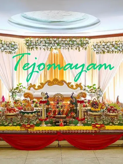 A wide view of a half-saree function setup with a red and white theme, showing the full stage and the elaborate plate arrangements.